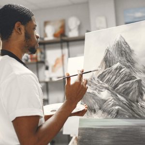 Artist concentrating onpainting. African man in painting class. Guy in a apron.